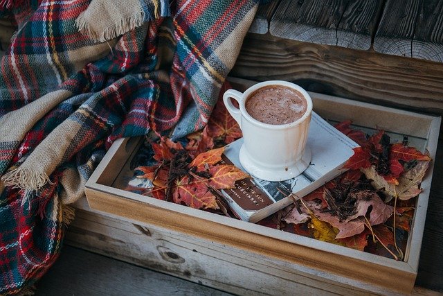 Cosy autumn scene with hot drink and blanket, symbolising seasonal self-care and online hypnotherapy for relaxation