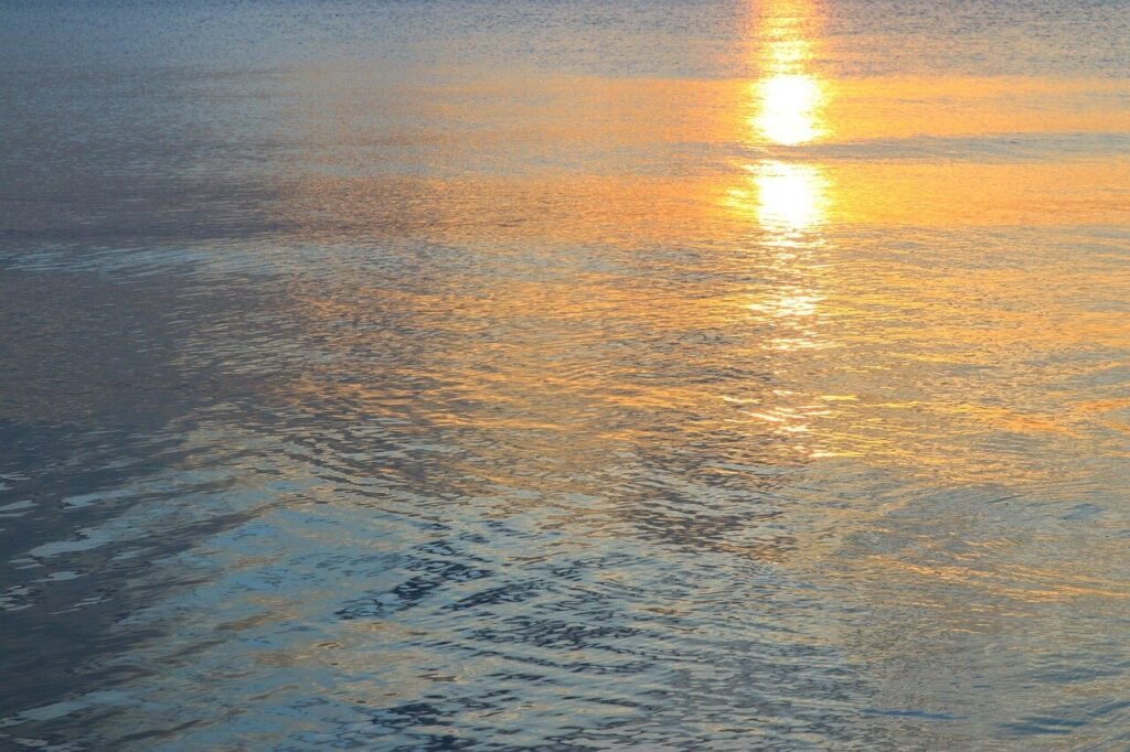 Golden light on calm water representing relaxation and awareness in hypnotherapy online.